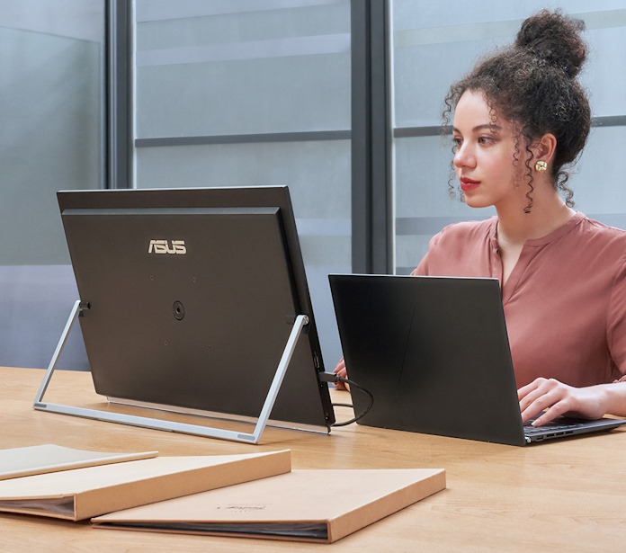 A woman works on her laptop using the ZenScreen MB27ACF for additional screen space