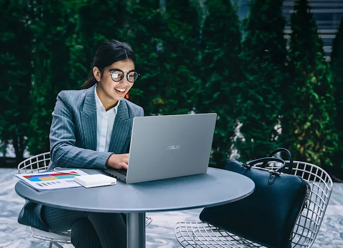 A young woman works on her laptop in an ourdoor space 