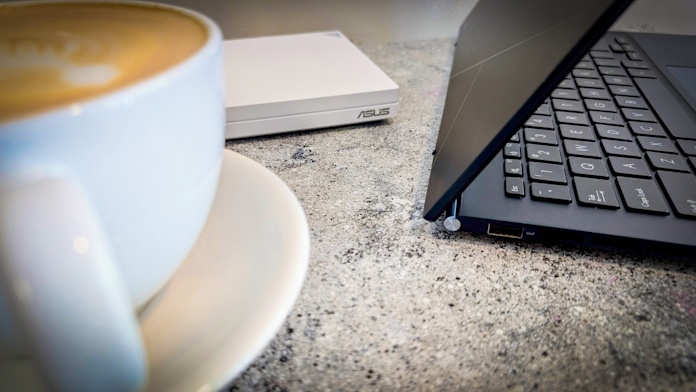 A travel router at a coffee shop with a cup of coffee and a laptop