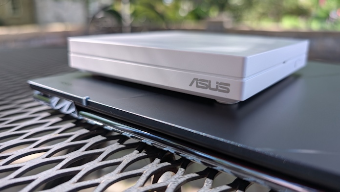 An ASUS travel router rests on an ASUS Zenbook laptop