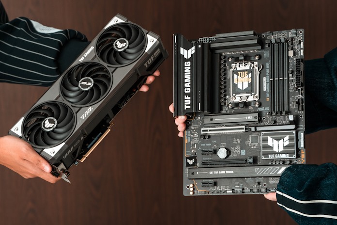 Two people holding out a TUF Gaming graphics card and motherboard into camera frame