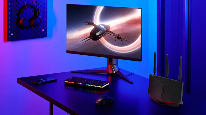 The ASUS RT-BE86U gaming router on a desk with a full PC gaming setup