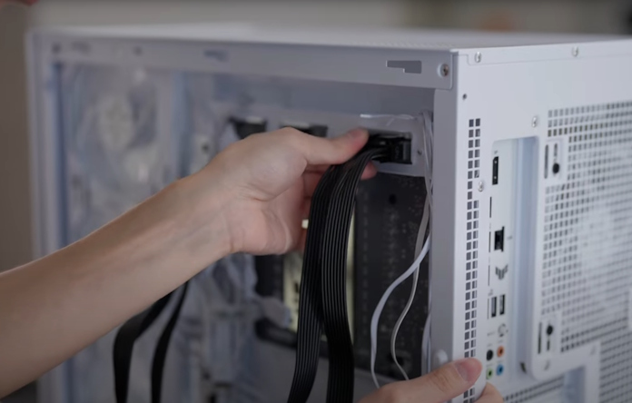 A young man plugging in cables to the backside of a BTF motherboard