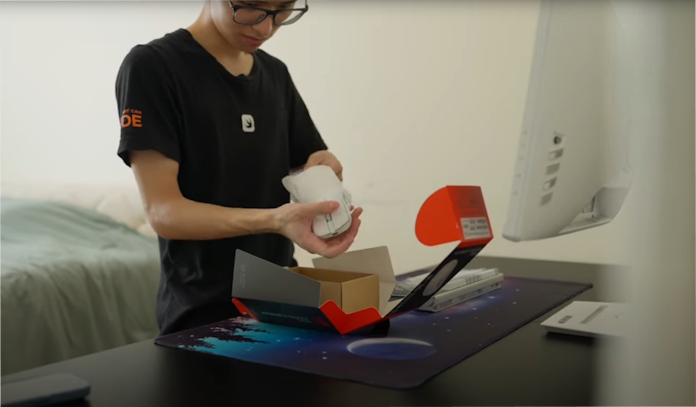 A young man pulls an ROG Keris II Origin gaming mouse out of its box