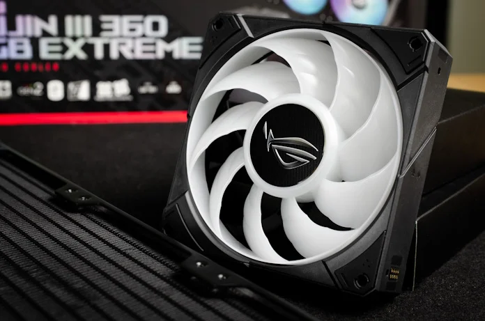 One of the ROG ARGB fans propped up against its box, with the product packaging in the background