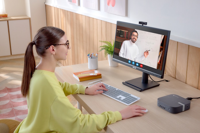 A woman participates in a video conference using an ASUS webcam monitor and a NUC mini-PC