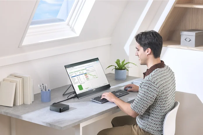 A young man works at a PC using a NUC and a movable ZenScreen monitor