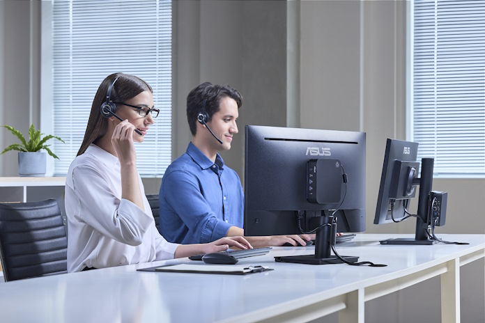 Two people work in a hotdesking office environment