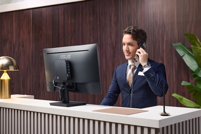 A man answers a telephone while working at a reception desk