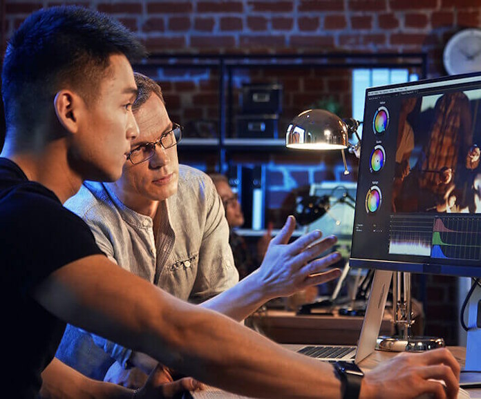 Two men analyze an image together at a professional content creation workstation