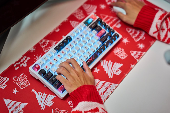A person games using the ROG Azoth X keyboard and the ROG Harpe II Ace gaming mouse on a piece of holiday wrapping paper
