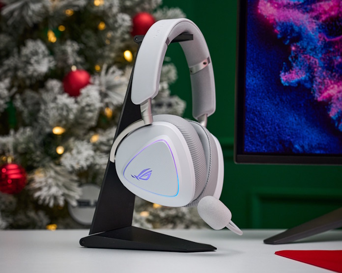 The ROG Delta II gaming headset in white, hanging from a headset holder with holiday decorations in the background