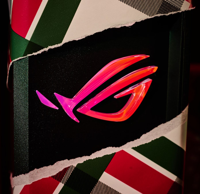 The ROG Strix GS-BE18000 gaming router being unwrapped, with the ripped paper exposing the glowing ROG Fearless Eye logo at the front of the router