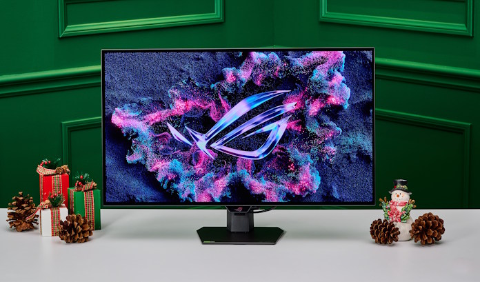 An ROG Strix OLED XG27AQDMG gaming monitor and a desk with ROG peripherals and holiday decorations