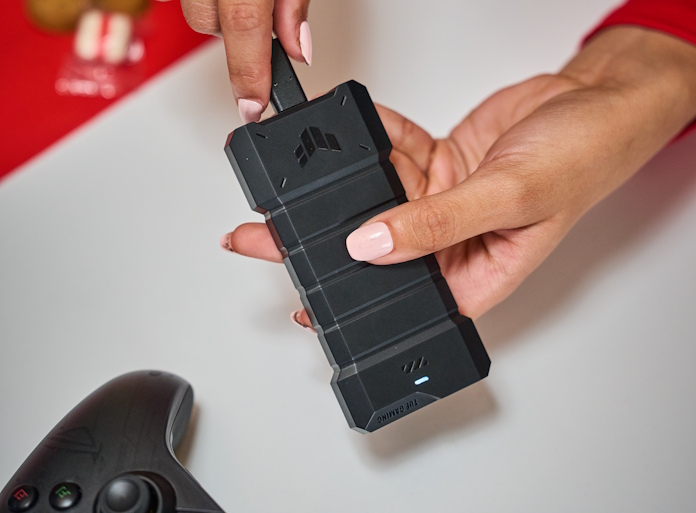 A woman plugs in the USB Type-C cable into the TUF Gaming A2 portable SSD enclosure
