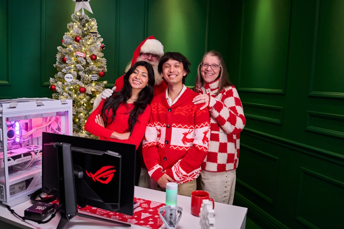 A group of people stand together behind a gaming desk with Santa 